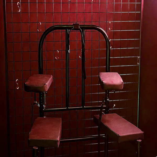 진홍 타일 벽 앞에 놓인 레드 패드 메탈 체어