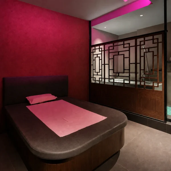 Private room with a padded treatment bed, pink lighting and timber lattice screen